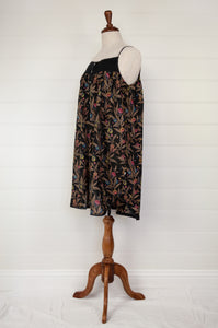 Ethically made pure cotton voile summer nightdress with adjustable straps and pintucked yoke, this nightie is in a wildflower print on black with broderie edging (side view).