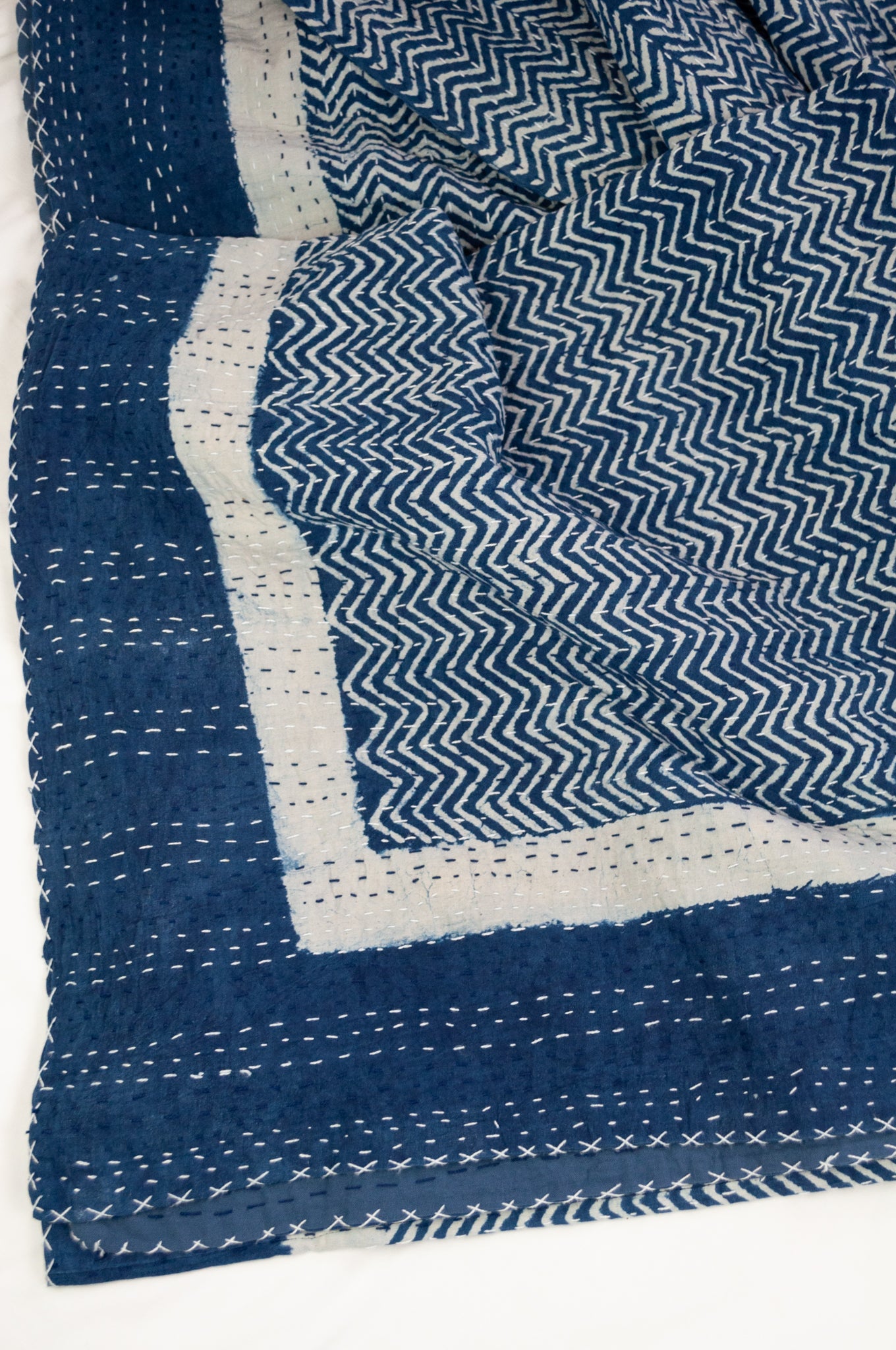 Block printed in indigo, blue and white kantha quilt hand made in Jaipur, featuring chevron pattern and plain blue and white border.