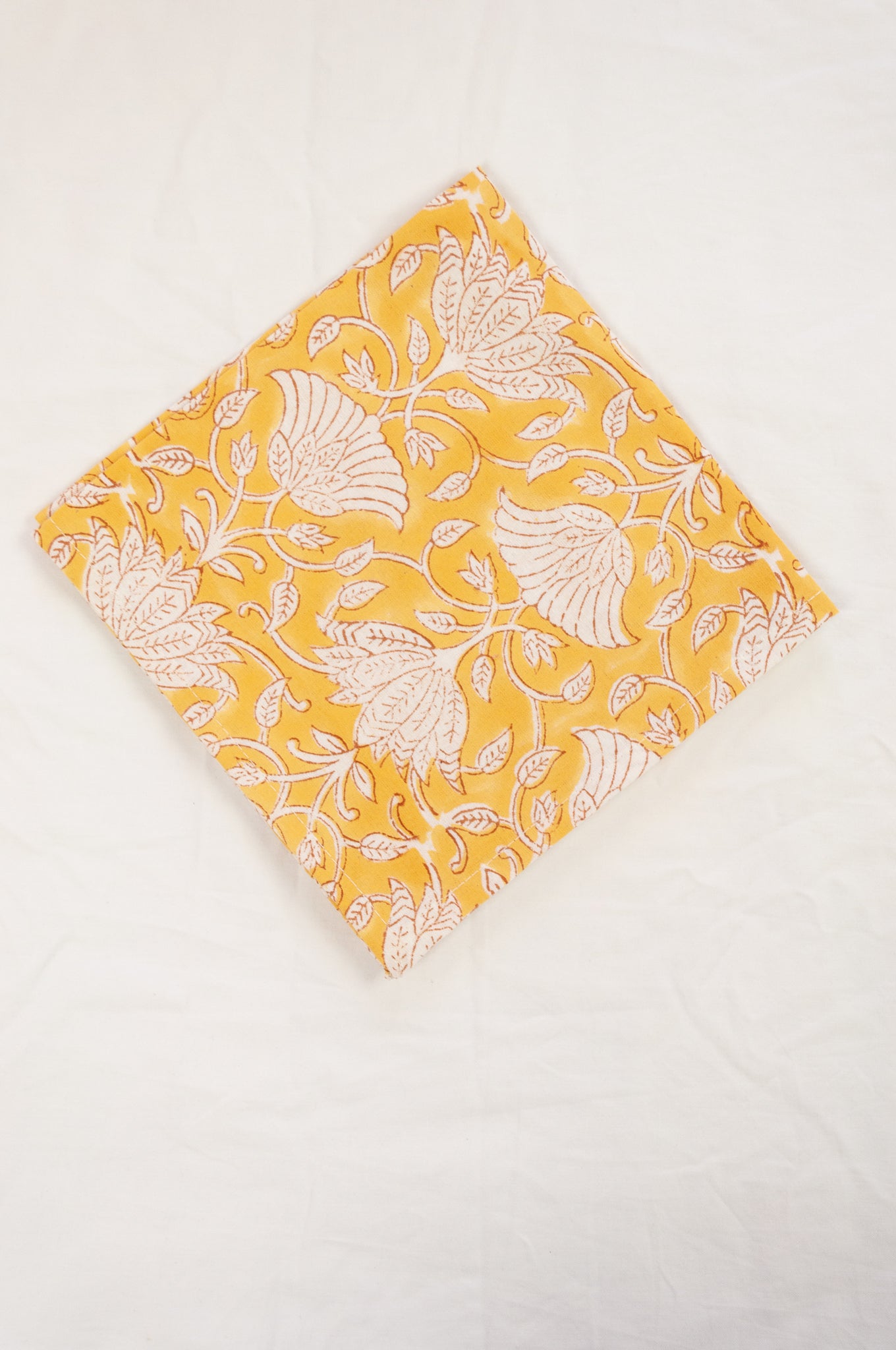 Cotton table napkins, blockprinted by hand exclusively for Juniper Hearth, Sara floral in white on honey yellow.