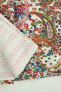 Handstitched cotton Kantha quilt paisley on a white background, with highlights in olive green, emerald, red, navy blue and tan
