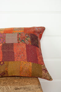 Vintage silk patchwork kantha bolster cushion in shades of orange, rose, burgundy, floral prints and highlights of lilac purple and olive green.