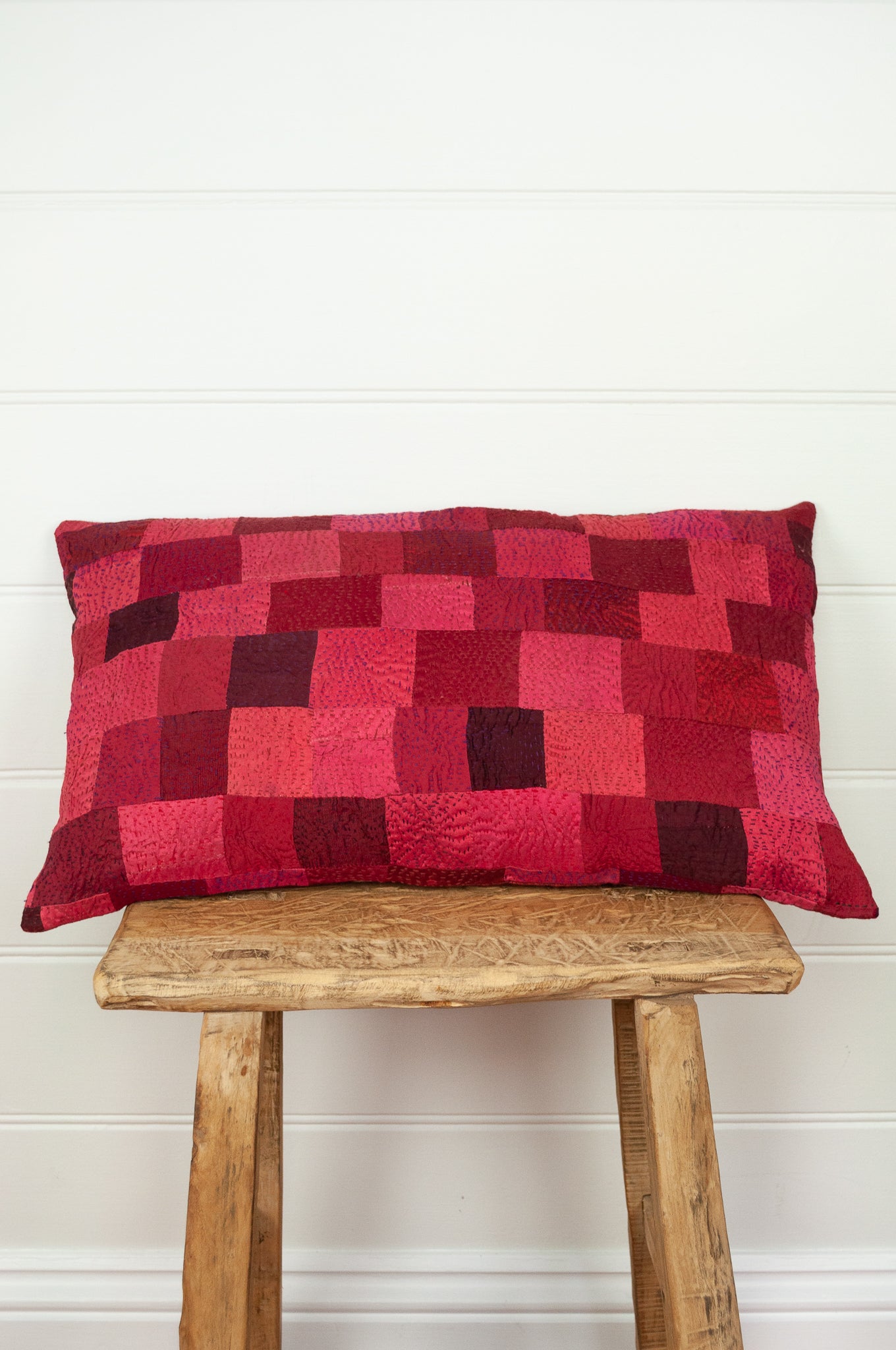 Vintage silk patchwork kantha bolster cushion is in rich tones of rose pink and red, with a dash of magenta