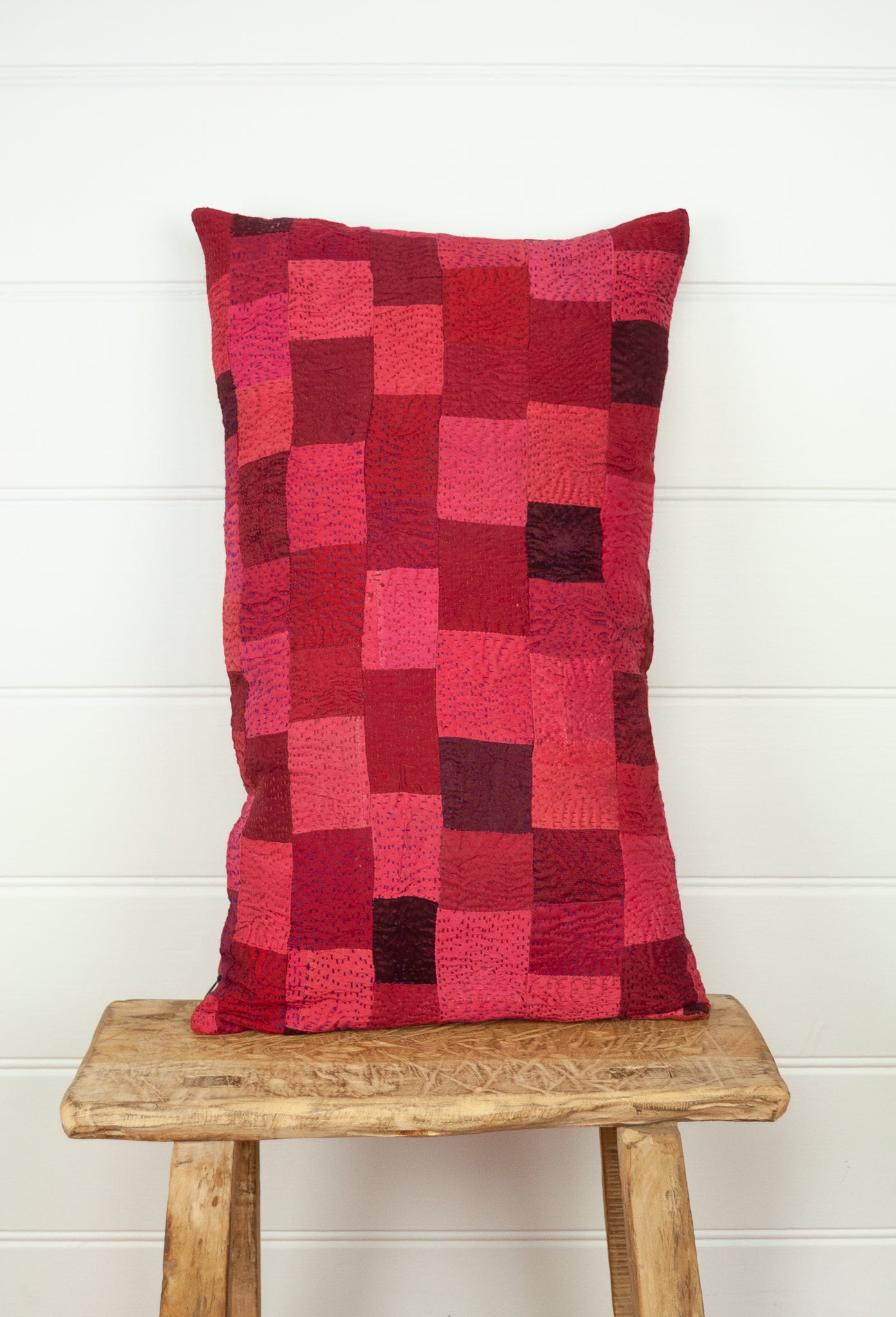 Vintage silk patchwork kantha bolster cushion is in rich tones of rose pink and red, with a dash of magenta