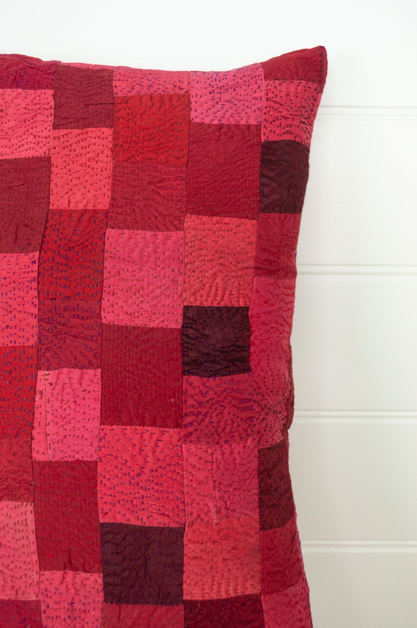 Vintage silk patchwork kantha bolster cushion is in rich tones of rose pink and red, with a dash of magenta