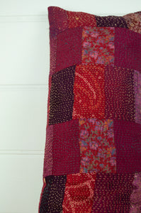 Vintage silk patchwork kantha bolster cushion 20x60cm is in shades of magenta, deep rose pink, and red.