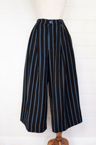 Maku Kosambi pants merino wool striped indigo, wide leg, fitted at waist with pleats, side pockets and button fly.