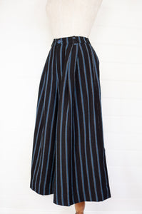 Maku Kosambi pants merino wool striped indigo, wide leg, fitted at waist with pleats, side pockets and button fly.