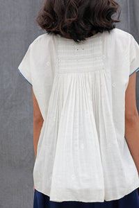 DVE Collection Adya one size top in white jamdani cotton, pin tucking at front, smock panel at back, loose fitting with cap sleeves and selvedge detailing to sides in blue.